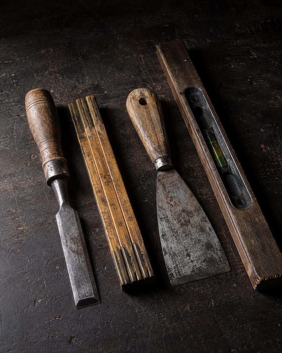 Worn professional hand tools laid out on a dark workbench